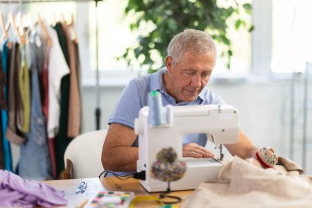 Mature man tailor sewing in workshopの写真素材