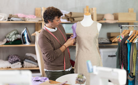 Man tailor adjusts clothes on mannequin