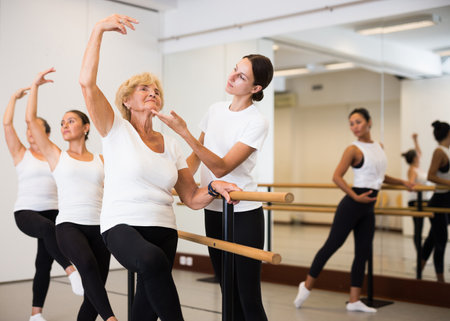 Various aged women exercising ballet moves with trainerの写真素材