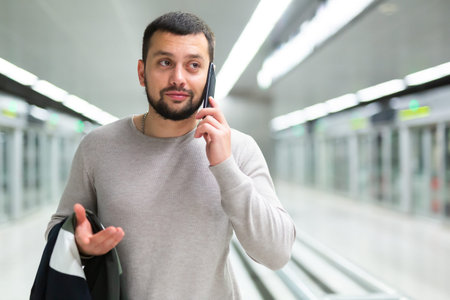 Bearded guy talking on phone on subway station platformの写真素材