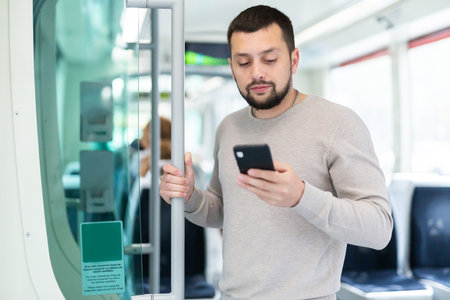 Young man using smartphone during trip in public transportの写真素材