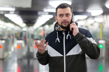 Man in jacket with a mobile phone near turnstile in subway