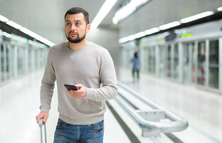 Portrait of confident man traveling on subway and using smartphoneの写真素材