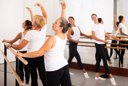 Group of women engaged in ballet in a dance studio performs a choreographic exerciseの写真素材