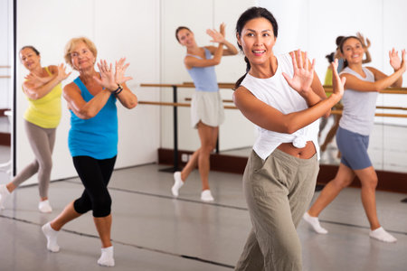 Positive asian woman practices energetic swing in a dance studio