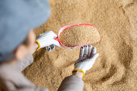 Young woman using a scoop to collect soy husks in an animal feed warehouseの写真素材