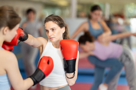 Female co-participant and woman sparring partners during training battle fight using technique of boxing match in sport gymの写真素材