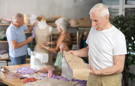 Elderly man reviewing paper pattern in training sewing workshopの写真素材