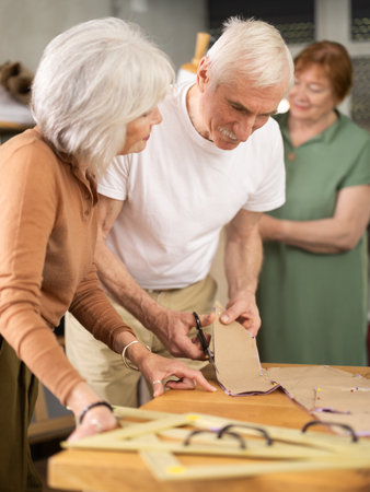 Elderly participants in sewing coterie learn sewing, communicate, cut pattern, work with mannequinの写真素材