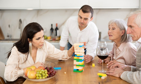 Positive woman playing jenga with husband and senior parents-in-law