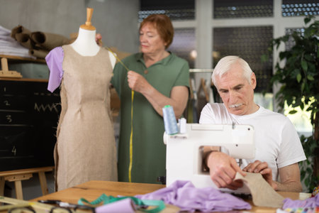 Elderly man and woman working with mannequin and sewing in classの写真素材