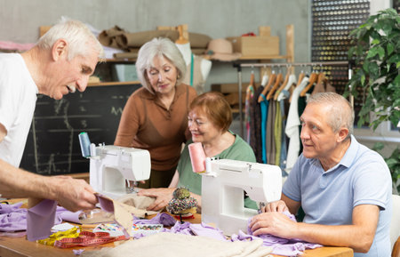 Group of senior learners enjoying sewing class in workshopの写真素材