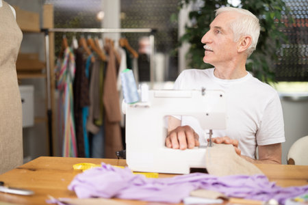 Experienced tailor using sewing machine to make garment in studioの写真素材