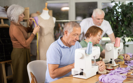 Elderly man stitching fabric on machine in sewing class for seniors