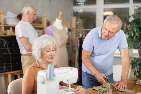 Some people talking, while others sew, work with mannequin, cut out dress patternの写真素材