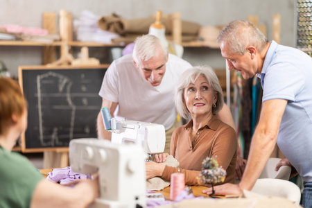 Aged woman stitching at machine during sewing class for seniorsの写真素材