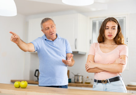 Daughter father scolding and yelling at her in home kitchenの写真素材