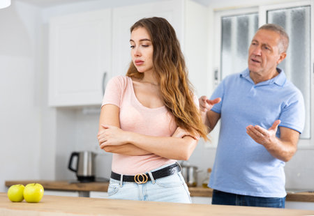 Elderly indignant father scolding adult daughter in kitchenの写真素材