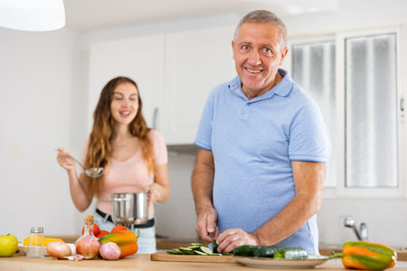 Happy father together with his adult daughter prepares a festive dinnerの写真素材