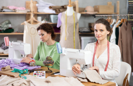Working in sewing workshop - two woman working at sewing machines, creating clothes