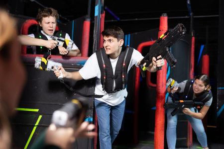 Portrait of excited people playing enthusiastically laser tag game two teams opposite each other in...