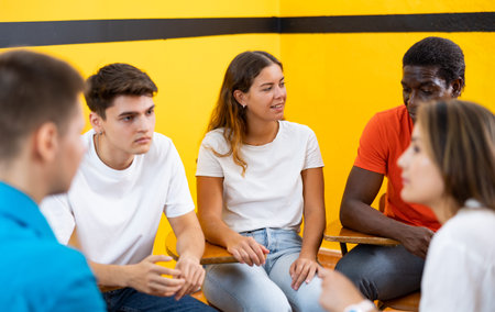 Friendly adult students chatting cheerfully while sitting in classroom