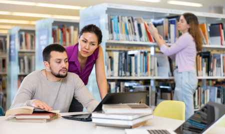 Woman and man looking at laptop screen together in library