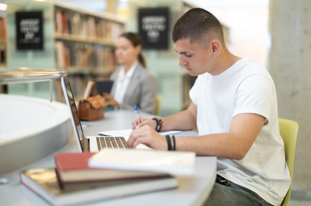 Student guy reading books and working on laptop