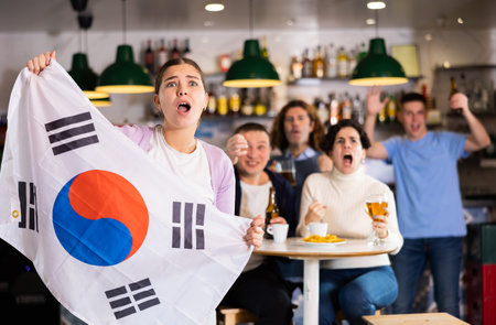Group of happy friends with flag of South Korea celebrating victory of their favorite team in beer barの写真素材