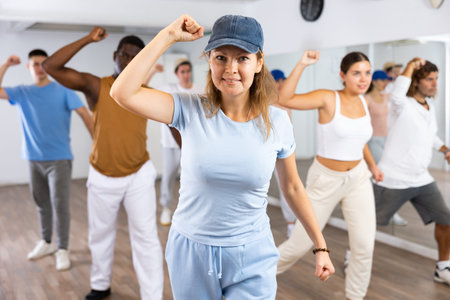 Excited sporty multiracial people practicing new movements steps during dancing training in studio