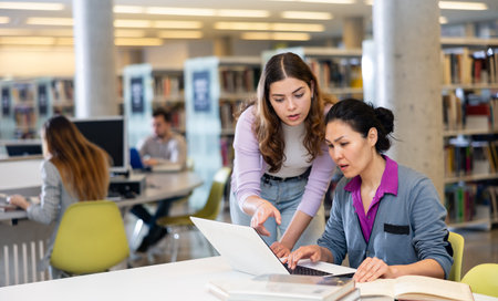 Two female colleagues working on joint project in library
