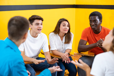 Friendly adult students chatting cheerfully while sitting in classroom
