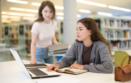 Female student asks woman working on laptop