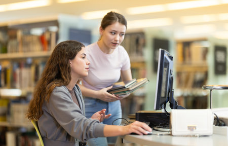 Two female students near the monitor in the libraryの写真素材