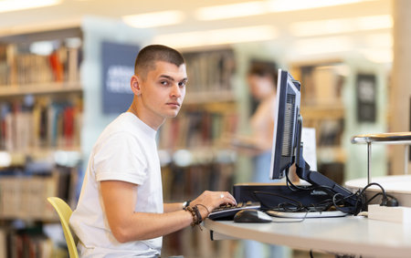 Male student works at computer in library
