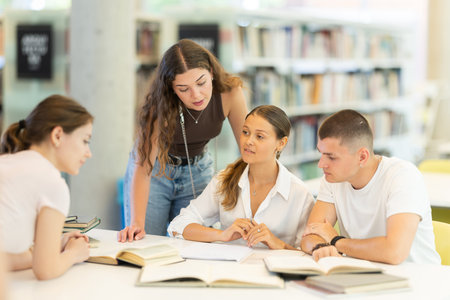 Group of students reading books and taking notes in library
