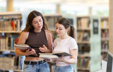 Two female students reading book in library