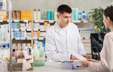 Man pharmacist looking for prescription on computer for buyerの写真素材