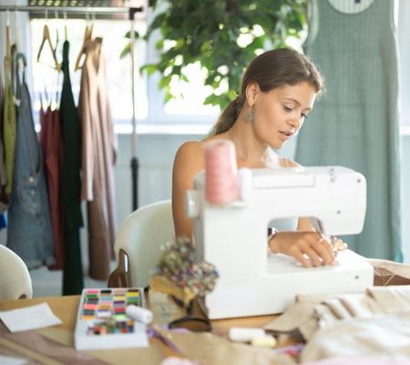 Female tailor using sewing machine to make garment in studioの写真素材