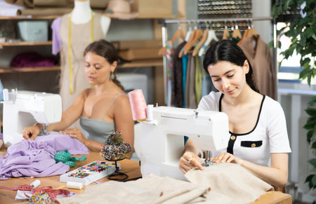 Female seamstresses working at sewing machines in tailoring studioの写真素材