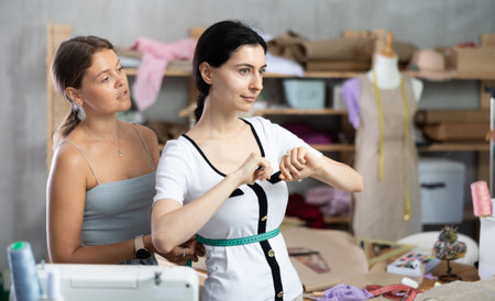 dressmaker takes measurements from the client