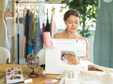 Young seamstress sewing on a machine in a workshopの写真素材