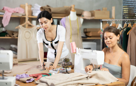 Two female tailors working on custom garment in studio