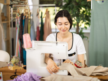 Female seamstress working on sewing machine in workshop