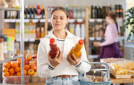 woman chooses juices against the background of buyersの写真素材