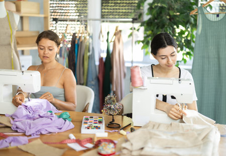 Female seamstresses working at sewing machines in tailoring studioの写真素材