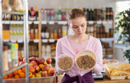 Female shopper chooses yakisoba - Japanese cuisine dish, while shopping in supermarketの写真素材