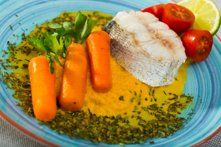 Steamed hake served with vegetable pate, carrots, lemon, greens and tomatoes
