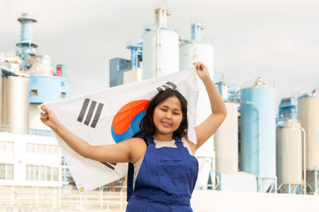 Portrait of teenage girl in blue overalls with flag of South Korea in her hands against the backdrop...