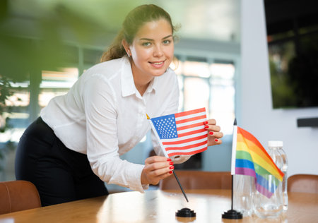 Young lady sets miniatures flags of LGBT and USA before international negotiationsの写真素材